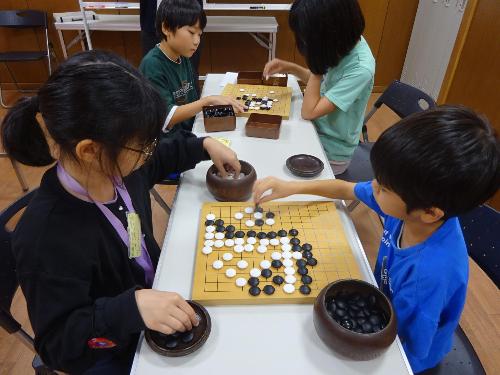 講師と対局をしている3人の小学生の写真