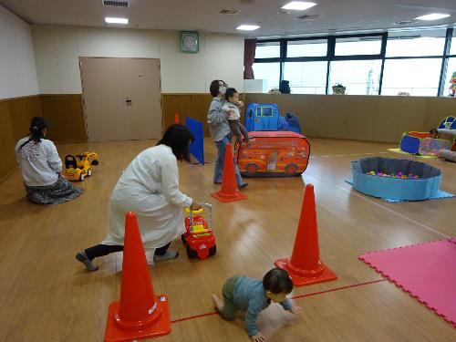 コンビカーやボールプール等の遊具で遊ぶ幼児親子たちの写真