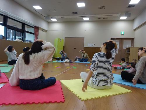 カラフルなマットの上でストレッチをしている幼児親子たちの写真