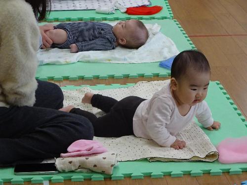 マットの上で寝ている赤ちゃんとハイハイをしている赤ちゃんの写真