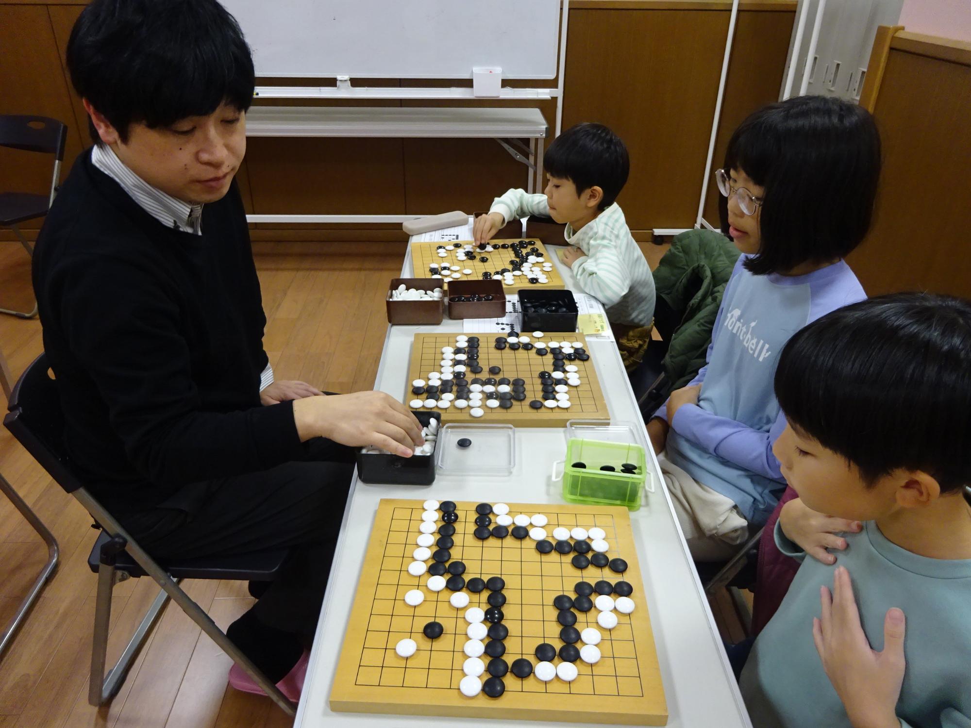 講師と対局をしている3人の小学生の写真
