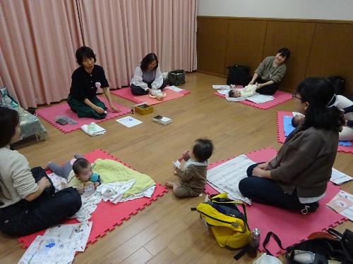 マットの上で寝たり遊んだり自由に過ごす4組の幼児親子の写真