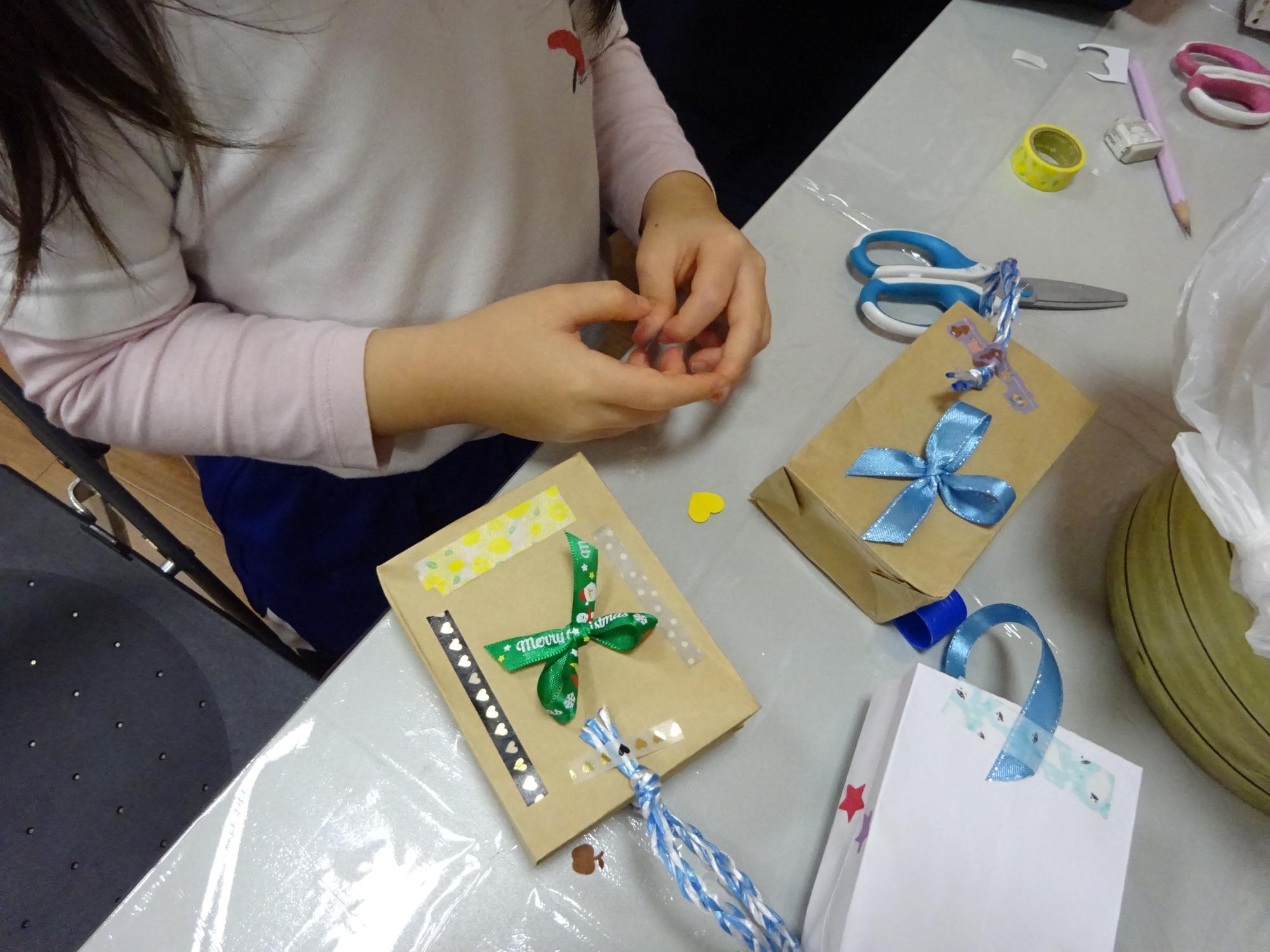 紙袋をリボンやシールで飾る児童の写真