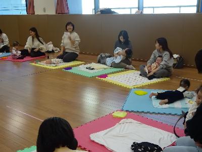 カラフルなマットの上でベビーマッサージをしている親子の写真