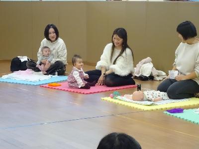 マットの上で講師とほほ笑み合う幼児親子の写真