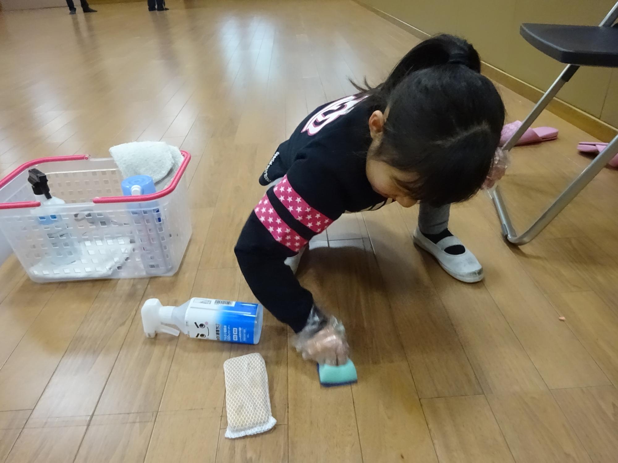 床のテープ後を掃除している小学生の写真