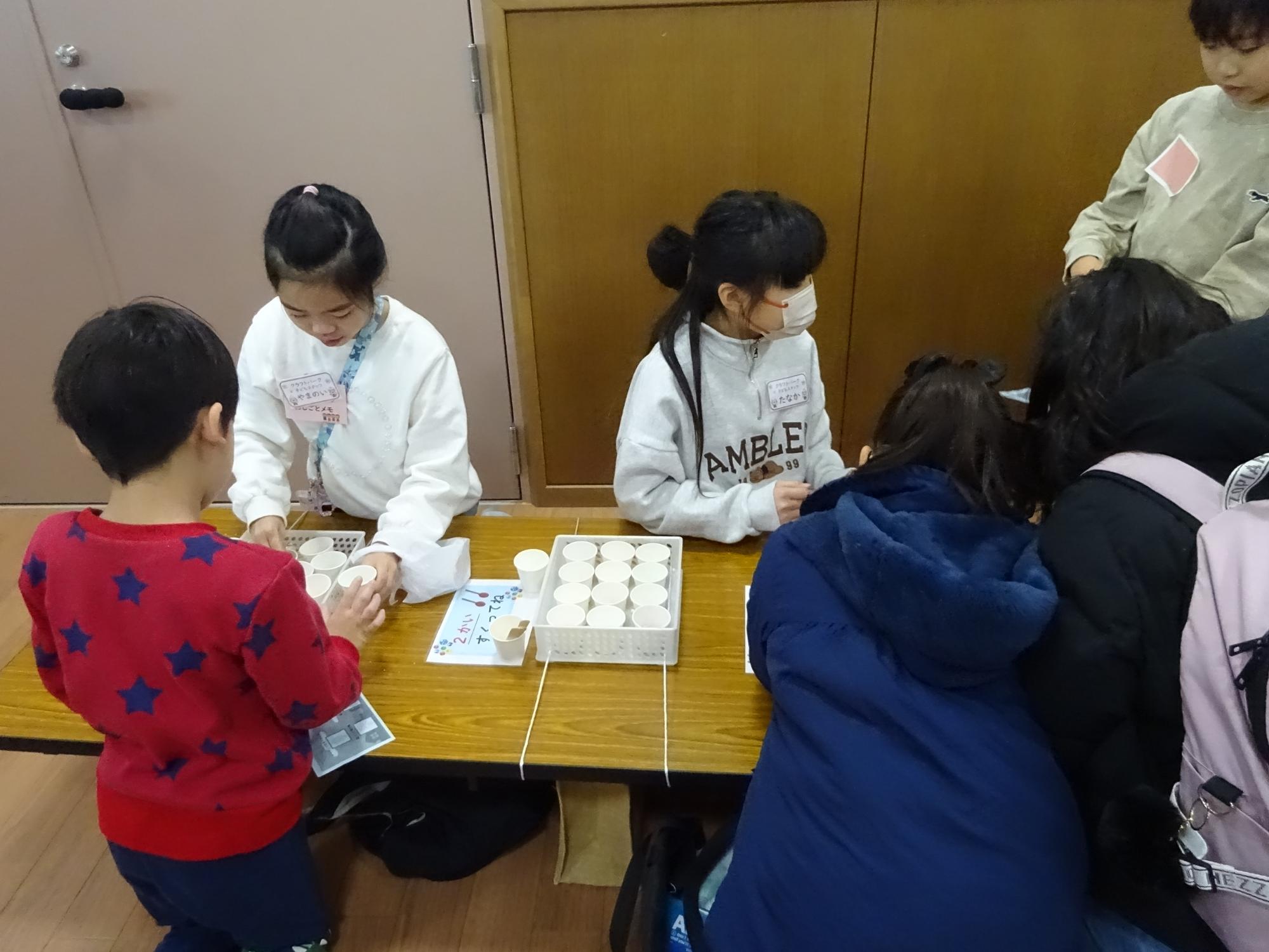 こどもスタッフが参加者に工作手順を教えている様子