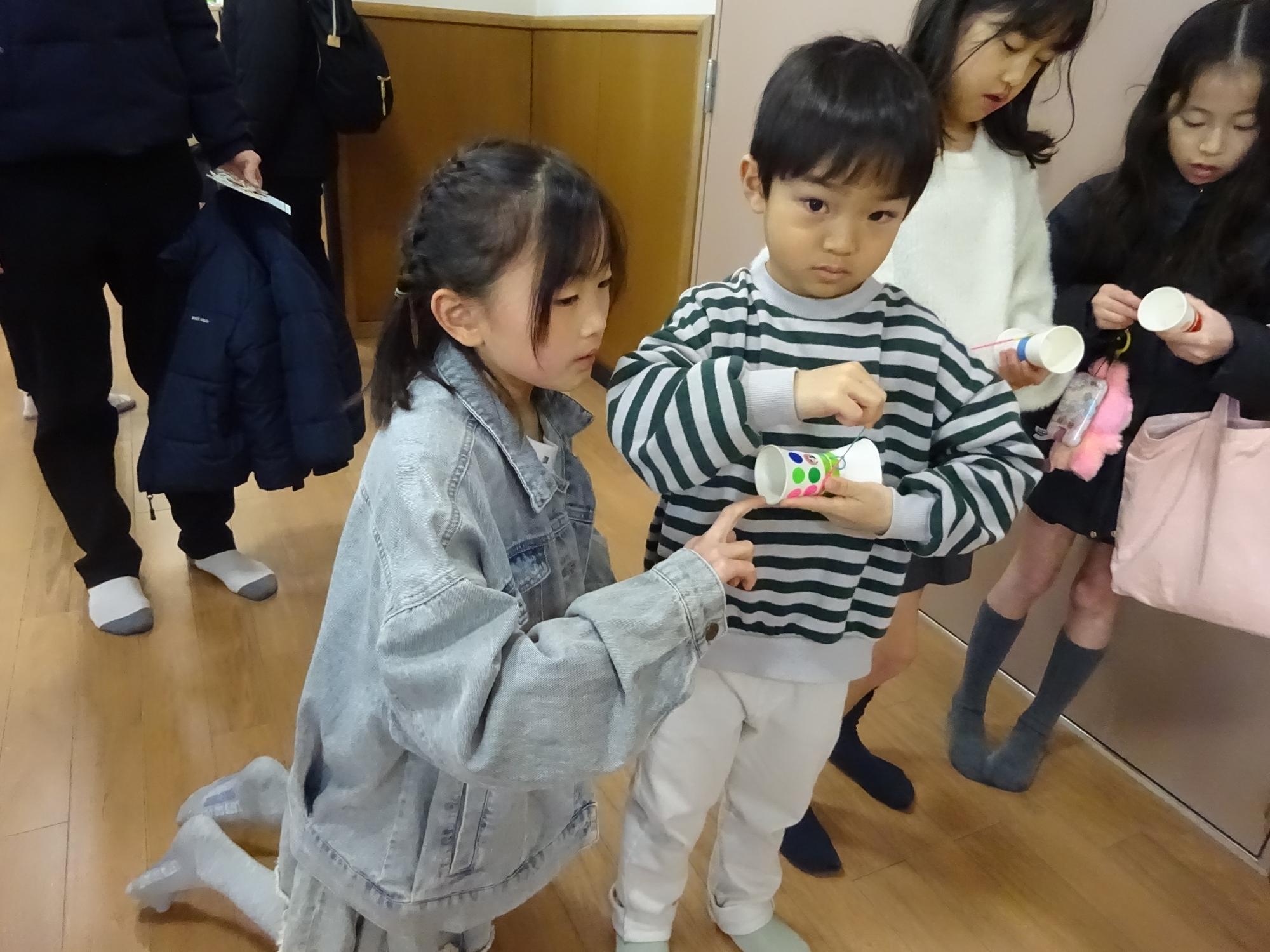 こどもスタッフが参加者に工作手順を教えている様子