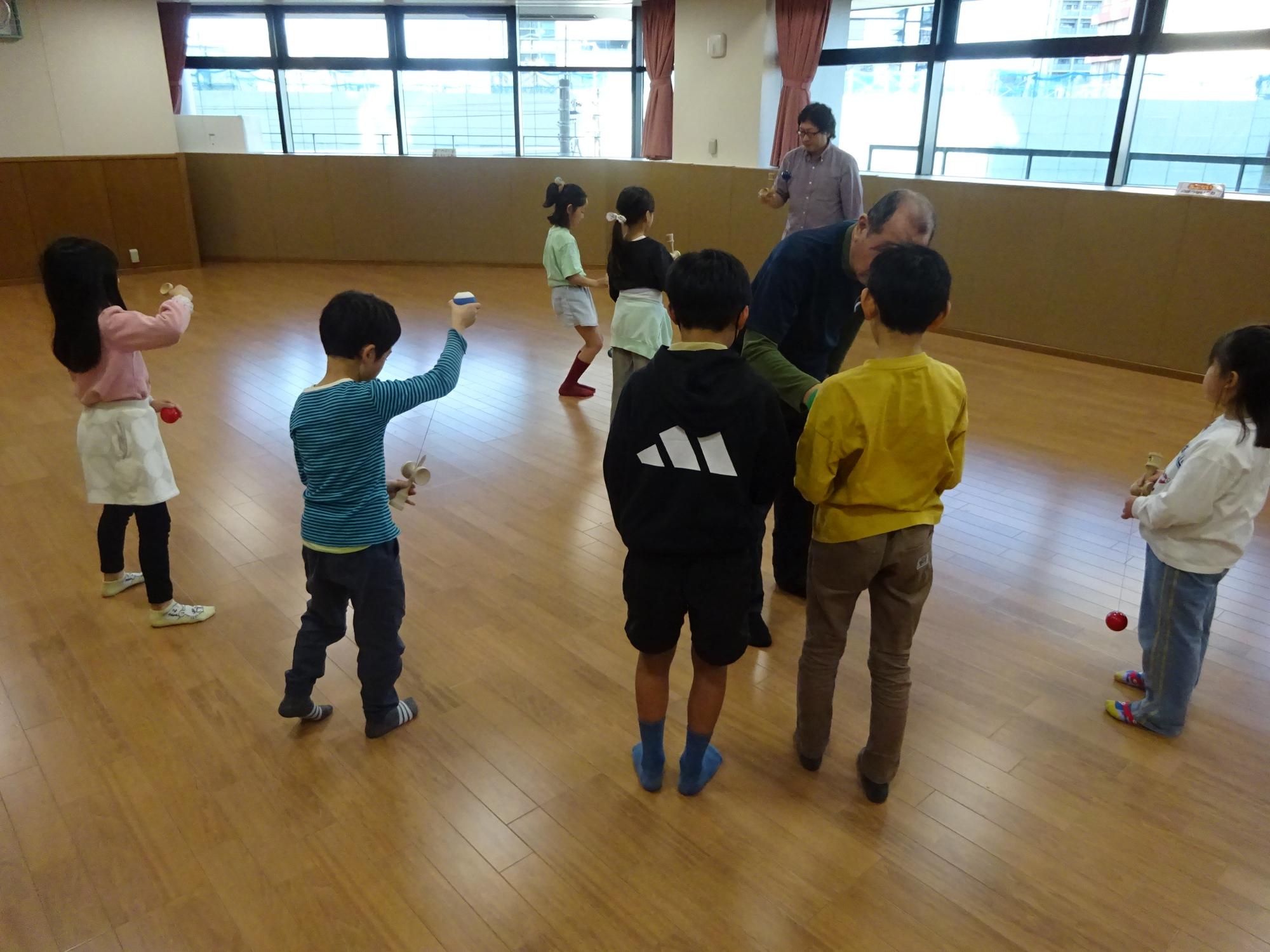 講師にけん玉を教えてもらっている様子