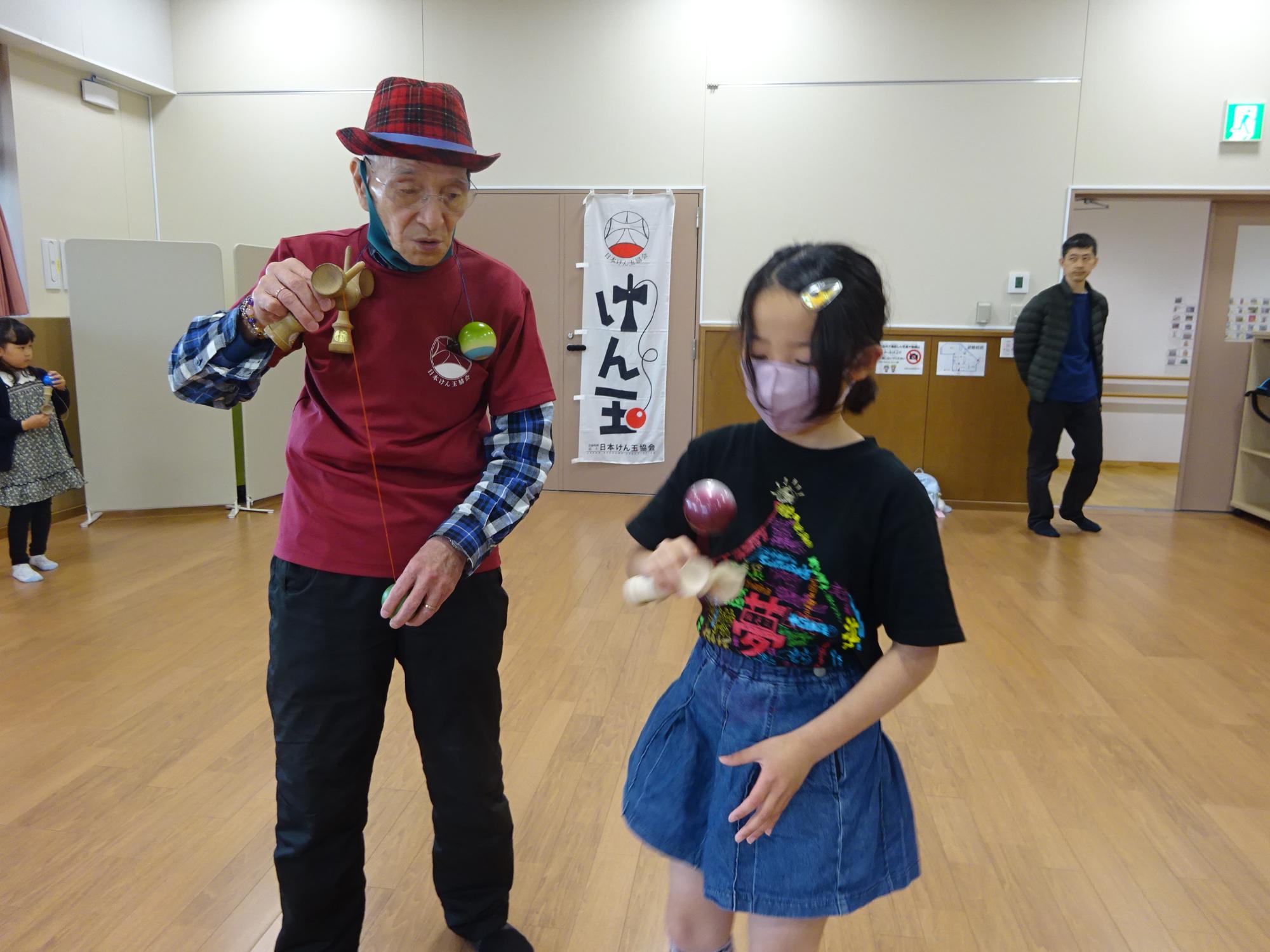 けん玉を教えてもらっている様子