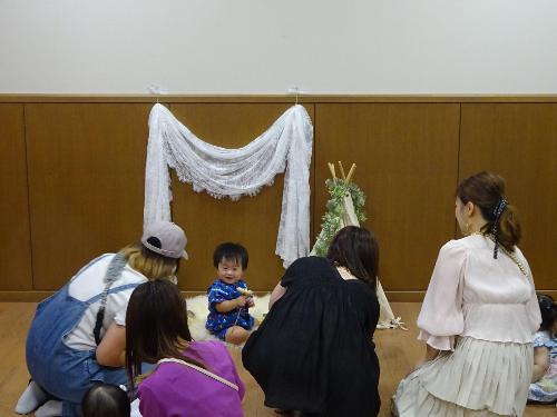 撮影ブースに座る幼児の写真を撮っている大人たちの写真