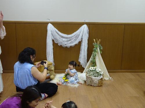 撮影ブースに座る幼児と写真を撮っている大人の写真