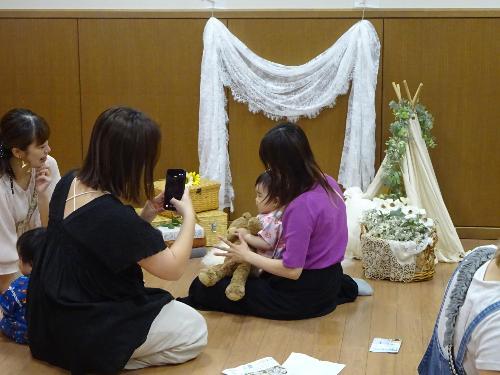 撮影ブースに座る幼児親子の写真を撮っている大人の写真