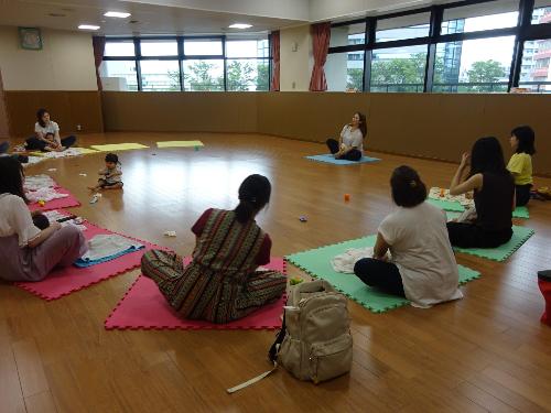 円形になって親子ヨガをする参加者たちの写真