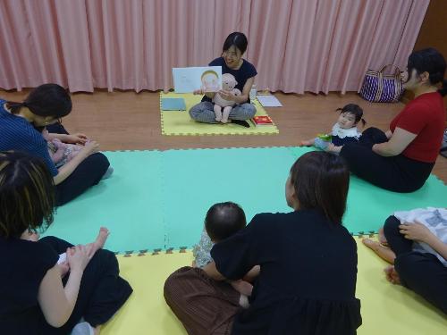 絵本の読み聞かせを聞いている幼児親子たちの写真