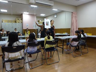 大きな鏡の前で講師の説明を聞いている子どもたちの写真