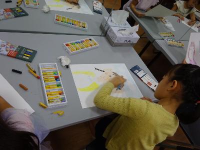 クレヨンで自画像を描いている子どもの写真