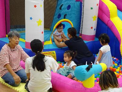 大型のエアー滑り台で遊ぶ幼児親子たちの写真