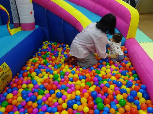 大型遊具のボールプールで遊んでいる乳幼児親子の写真