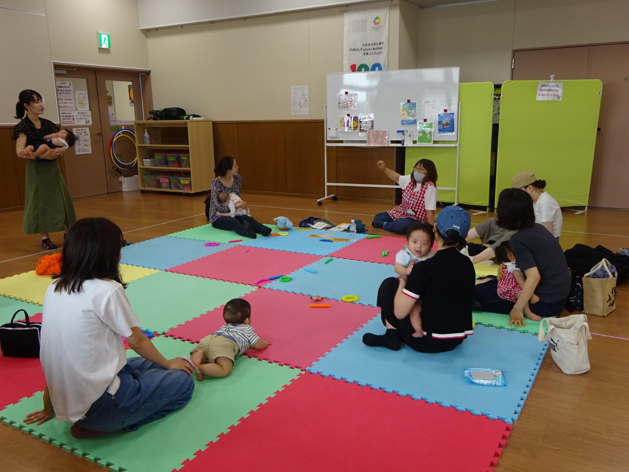 保育士のアドバイスを聞いている乳幼児親子たちの写真
