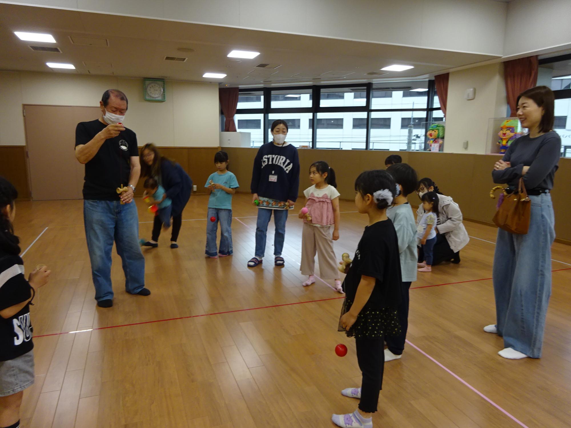 講師のけん玉の技を見ている子どもや保護者たちの写真