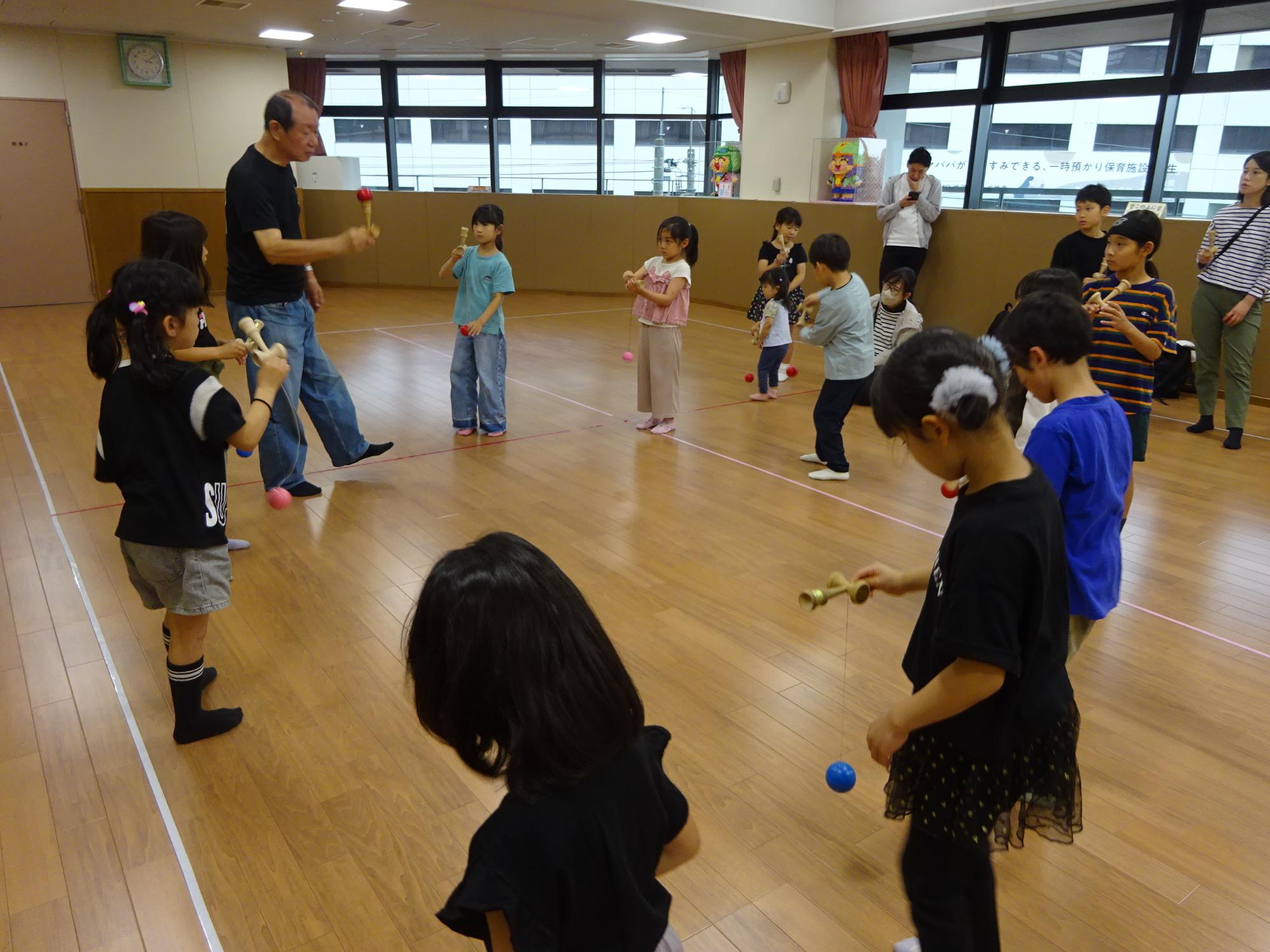 けん玉の練習をしている子どもや保護者たちの写真