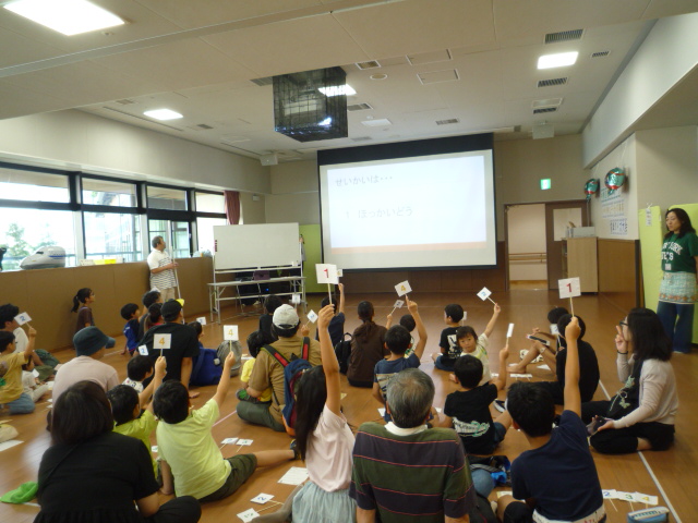 クイズの回答番号の札を上げる参加者たちの写真