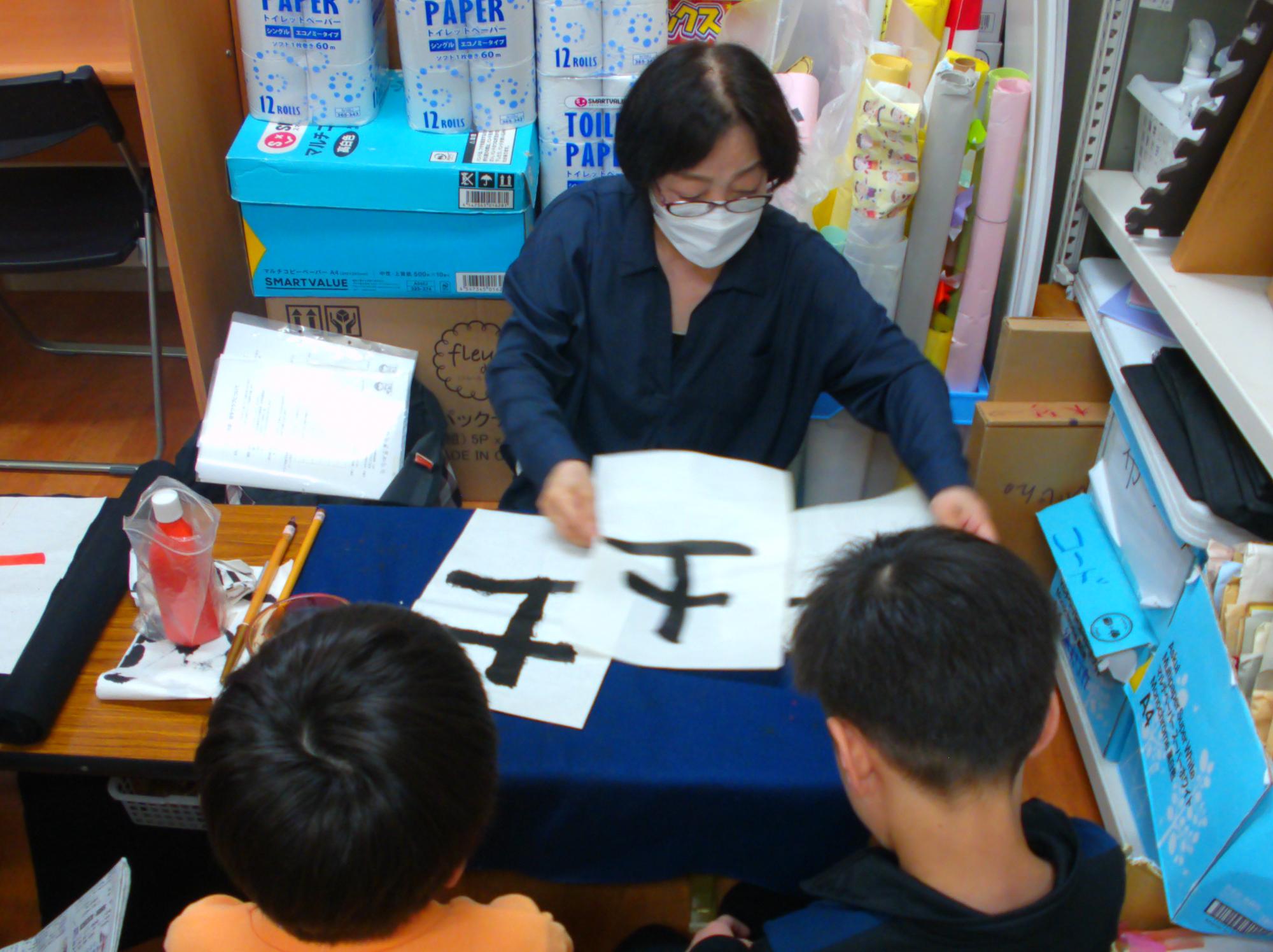 子どもたちが書いたものの確認を先生がしている写真