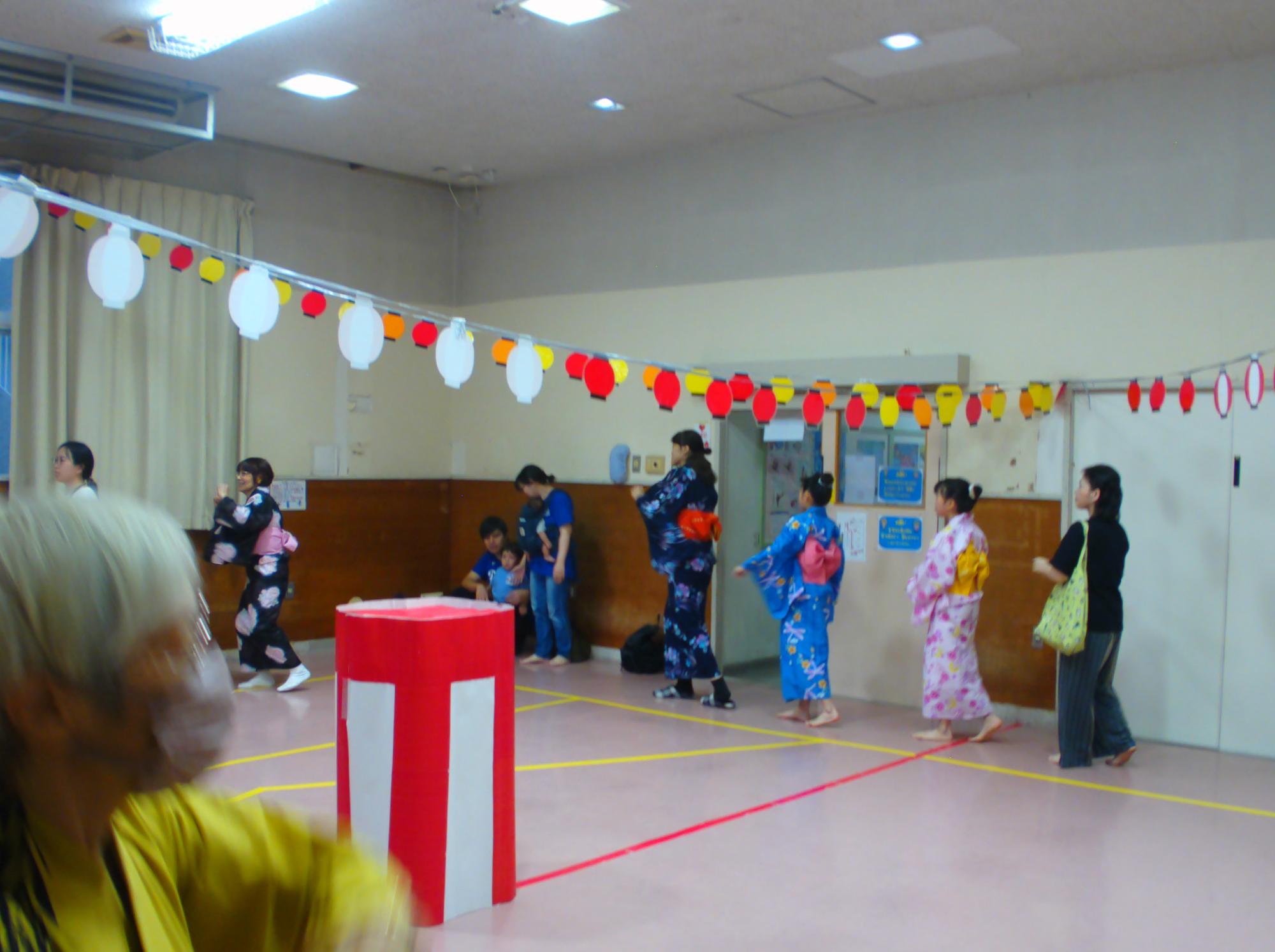 集会室でプロの方の真似をしながら盆踊りを踊っている写真