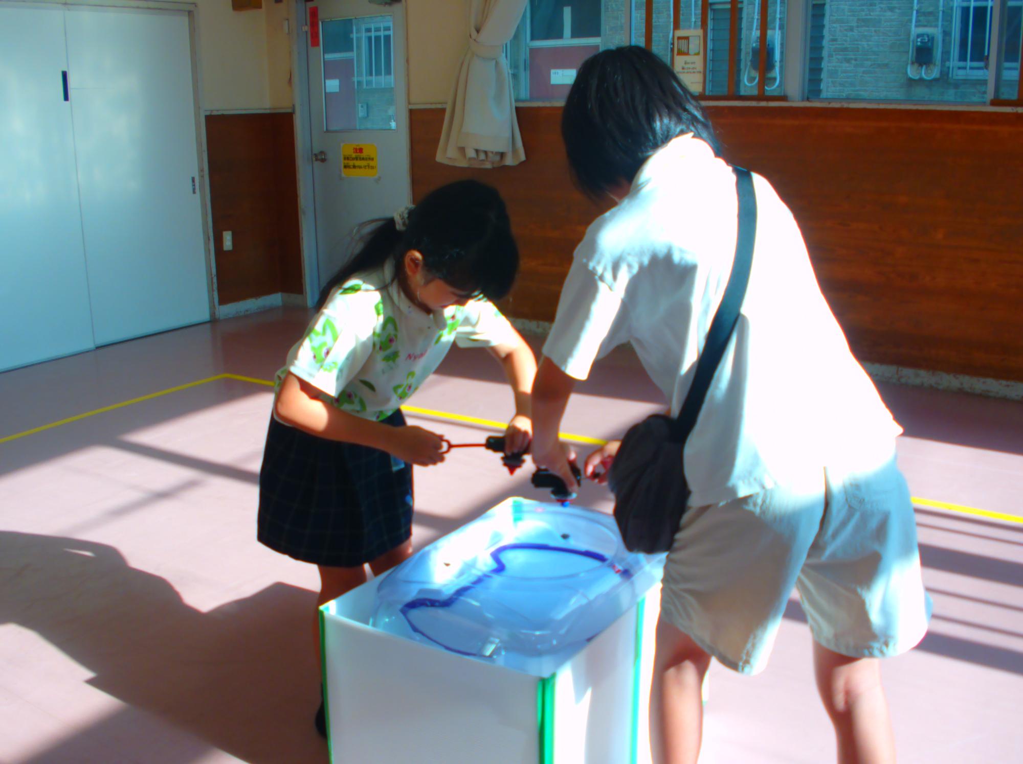 2人の小学生がベイブレードで対戦している写真