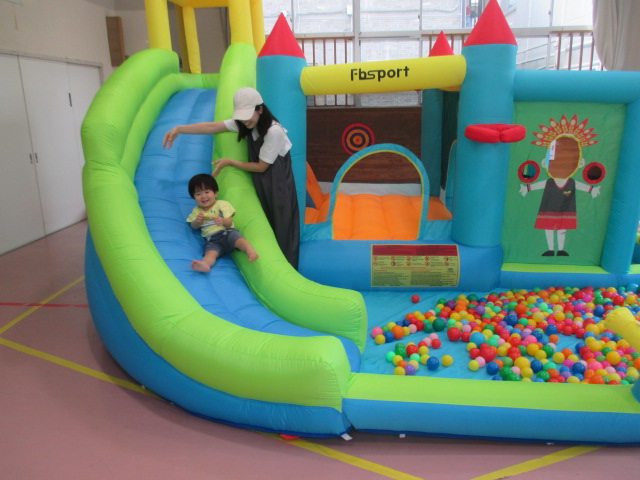 楽しそうにすべり台をすべる子どもと見守る母親