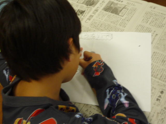 自転車防犯のポスターの下描きをしている男の子の写真