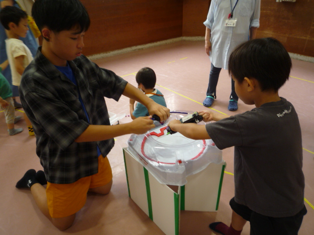中学生と小学生がベイブレードで勝負をする直前の写真