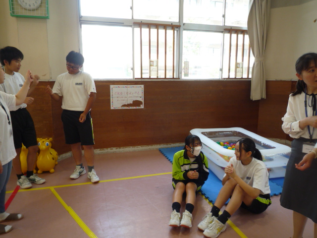 中学生が絵本の読み聞かせや手遊びの練習をしている写真