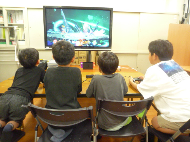 並んで仲良くゲームをするこどもたちの写真