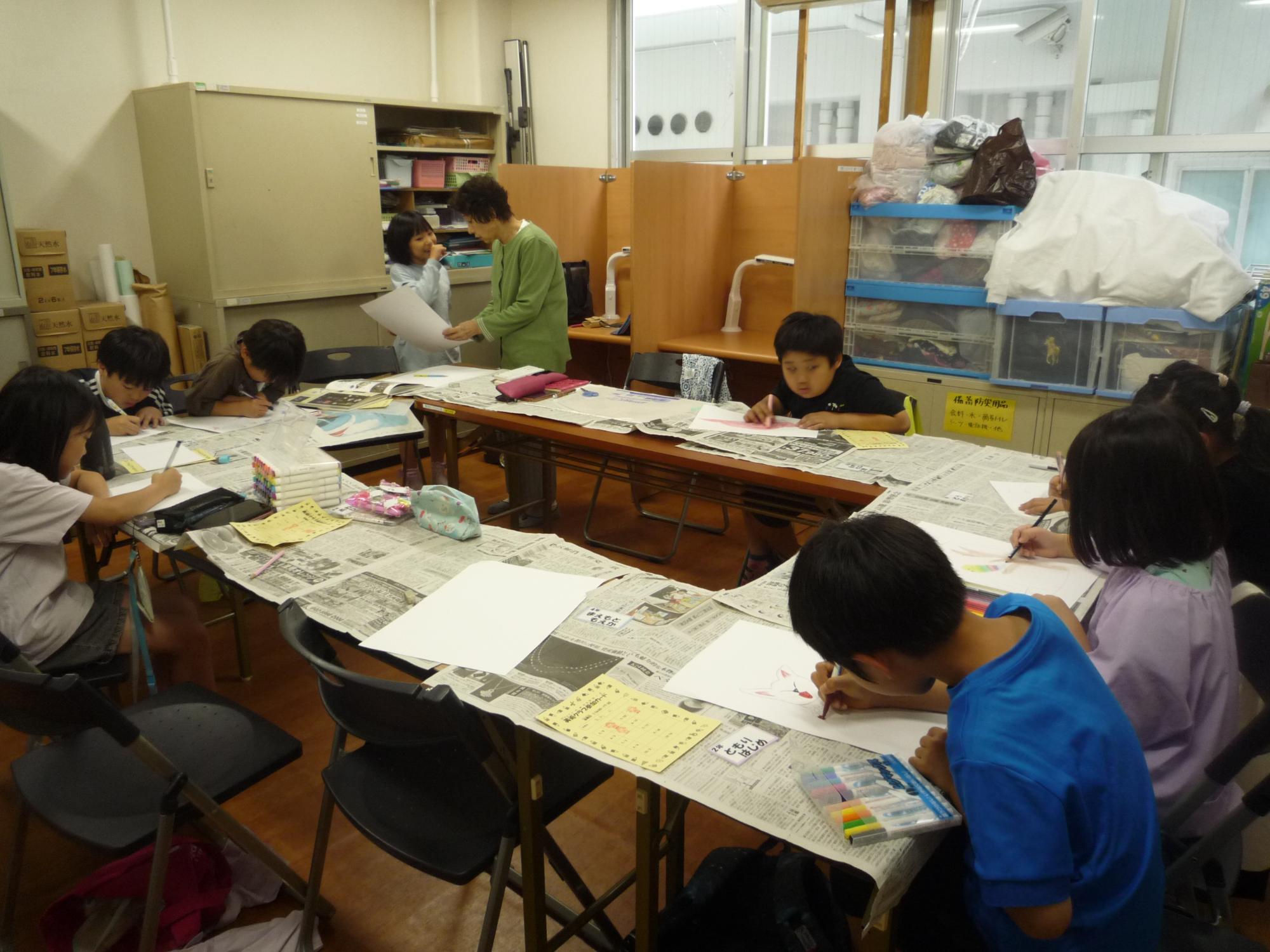 完成した絵を先生に見せる子どもと頑張って絵を描くこどもたち