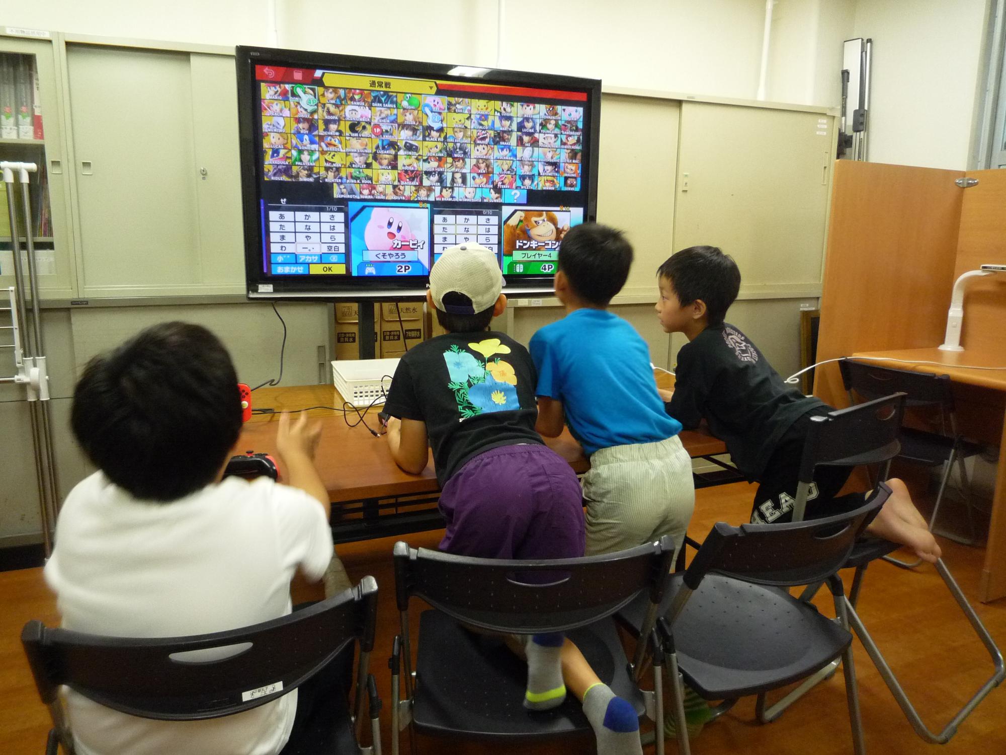 大きなテレビ画面でゲームを楽しむ小学生たち
