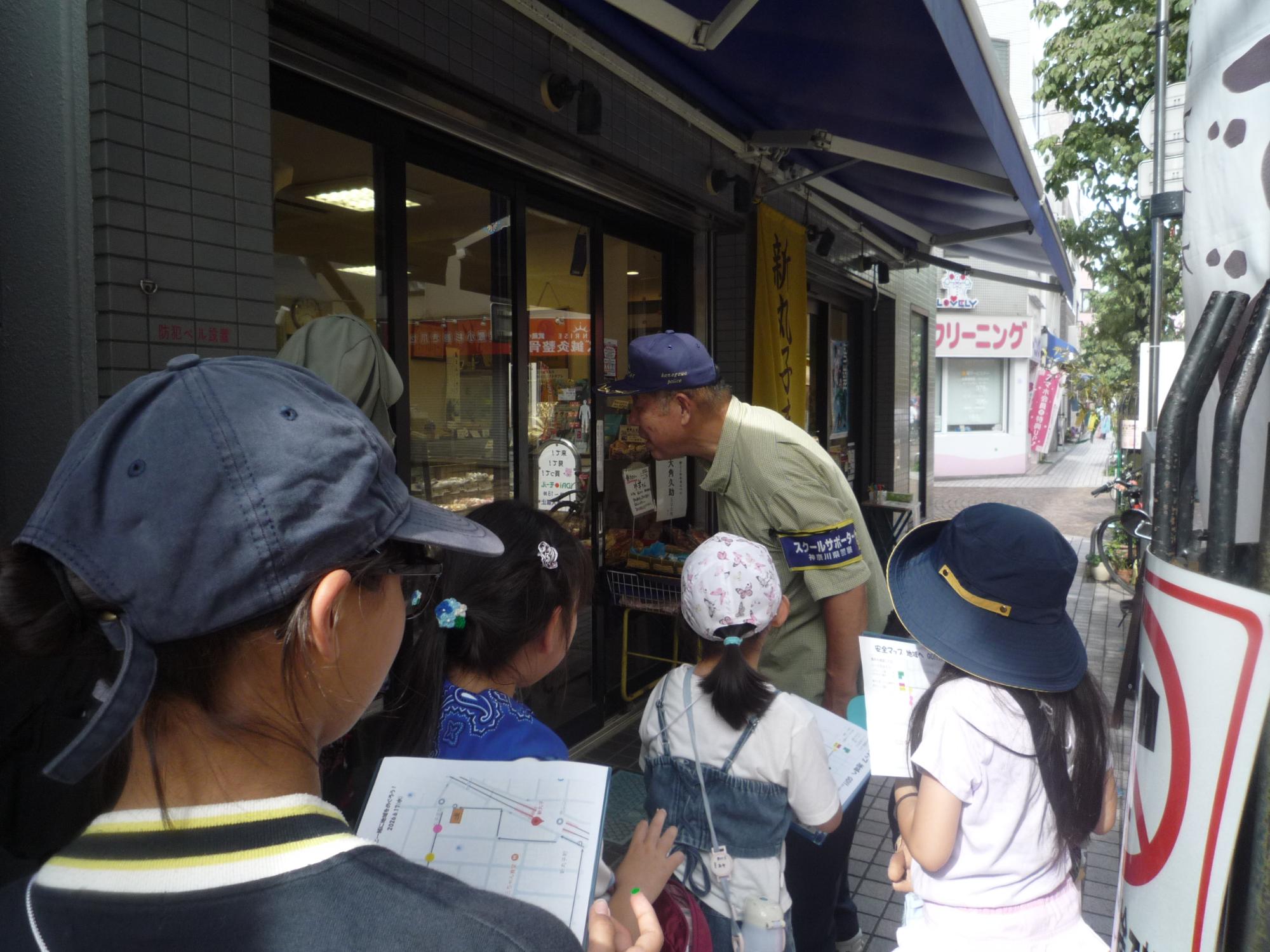 こども110番のステッカーが貼ってあるお店を見つけた小学生たち