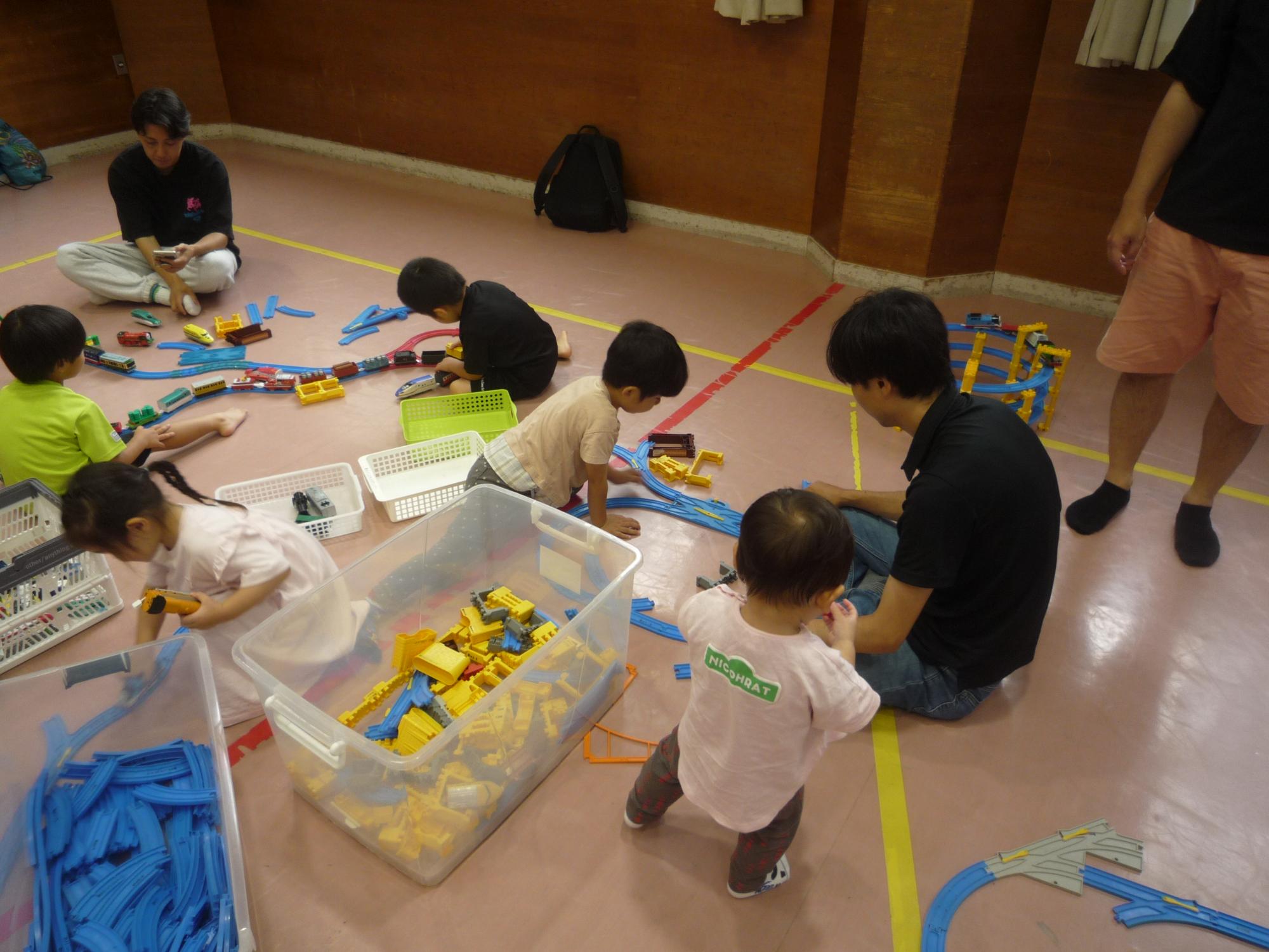 思い思いにプラレールを組み立てる親子たち