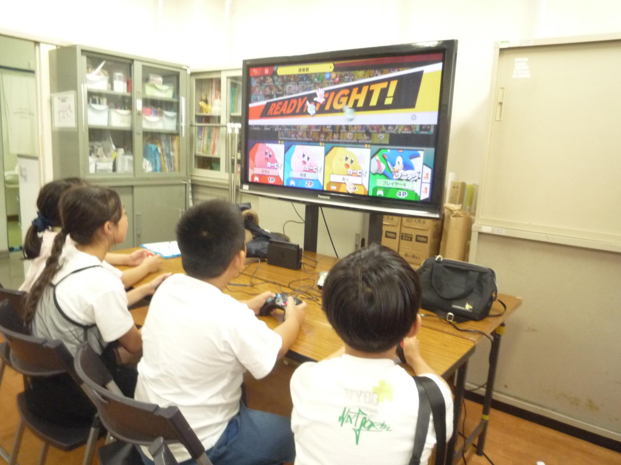 4人で並んでゲームを遊ぶ小学生
