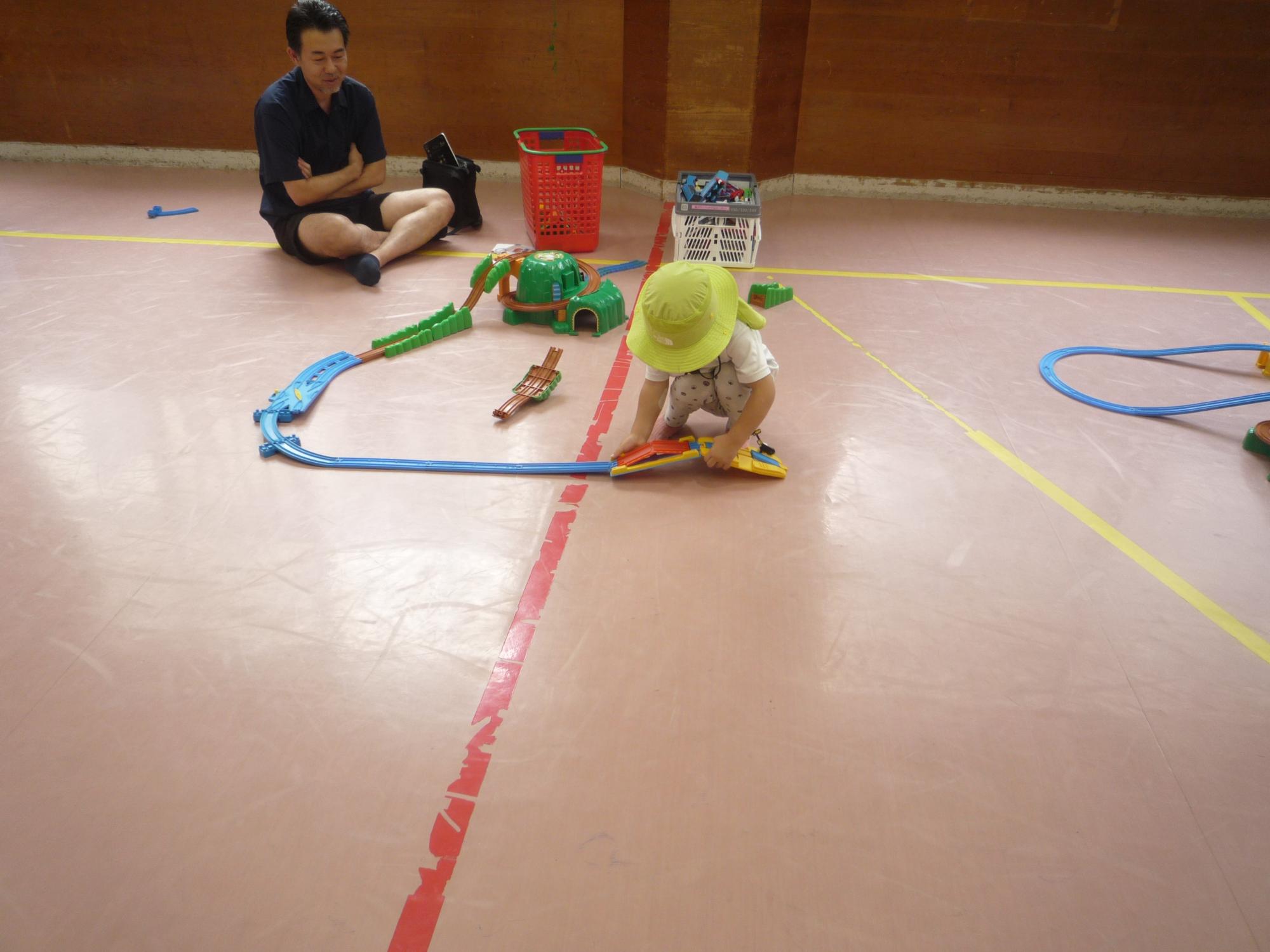 プラレールであそぶ幼児さんと見守る父親