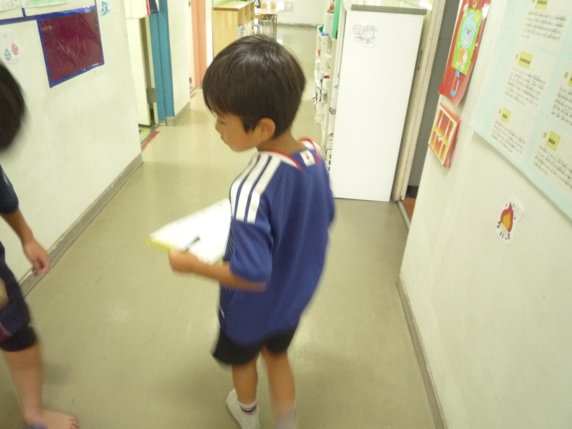 なぞとき問題をもって館内を歩く小学生