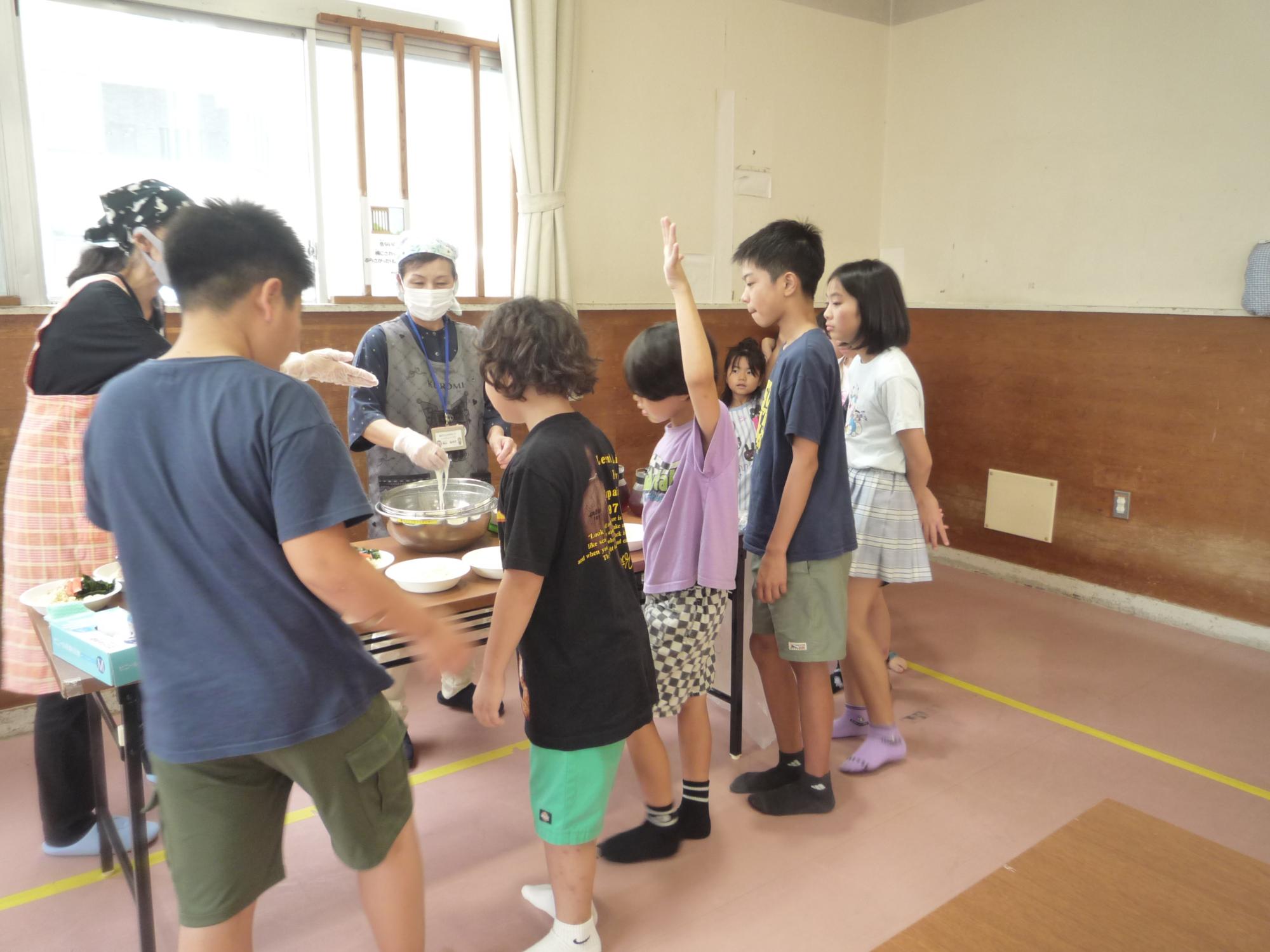そうめんをもらう列に順番で並ぶ小学生