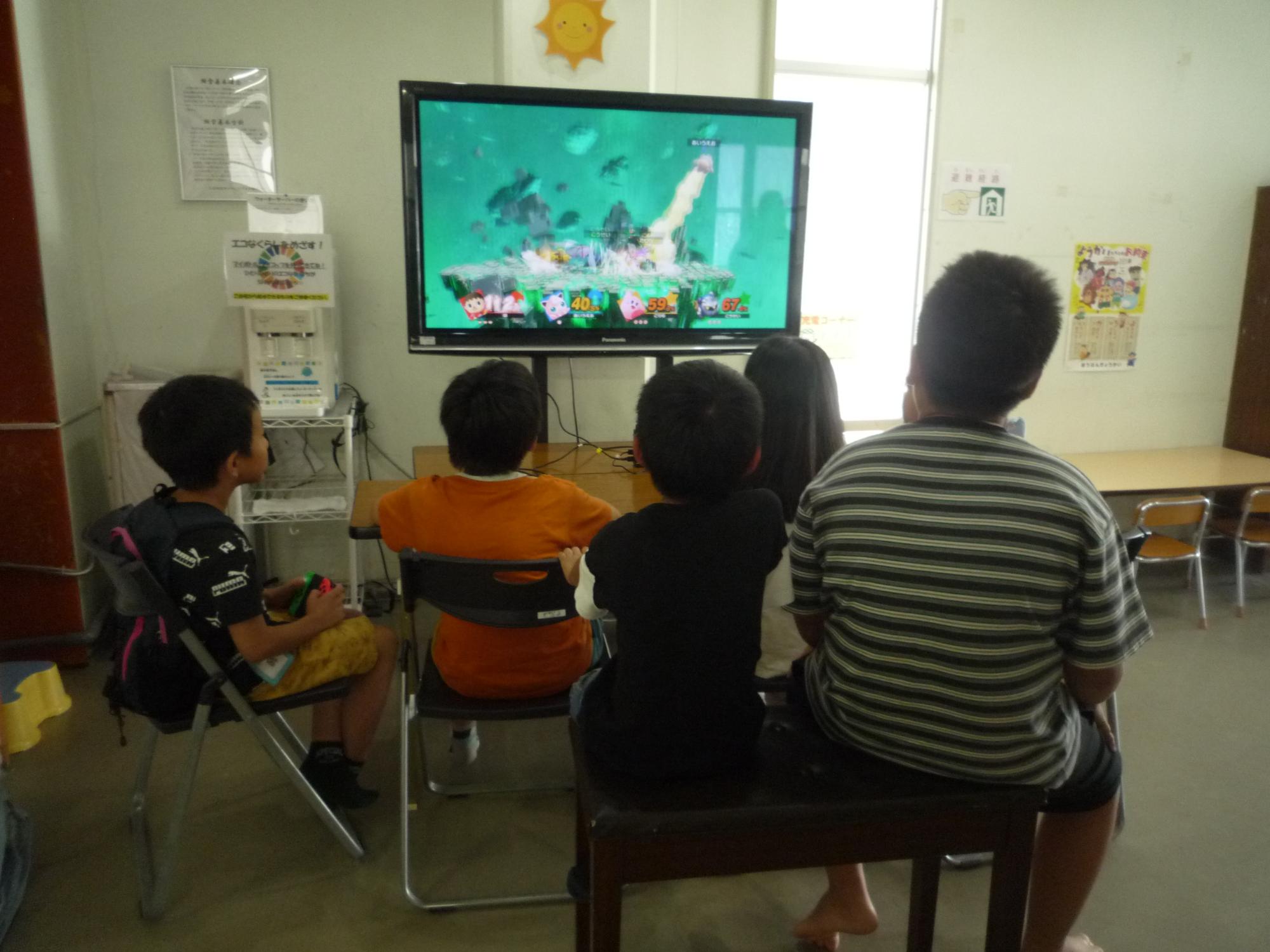 大きなテレビ画面でゲームを楽しむ小学生たち