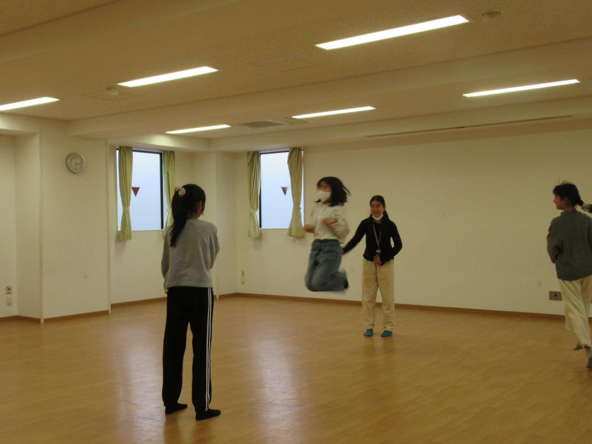 子どもたちが大縄で八の字飛びしている写真