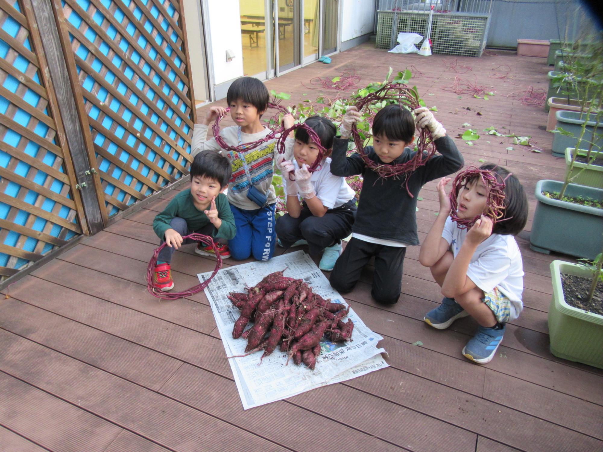 子どもたちがツルで作ったリースを顔にはめてポーズを撮っている写真