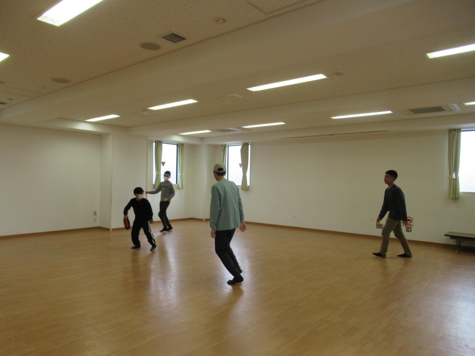 フリスビーで遊ぶ小中学生4人組の写真