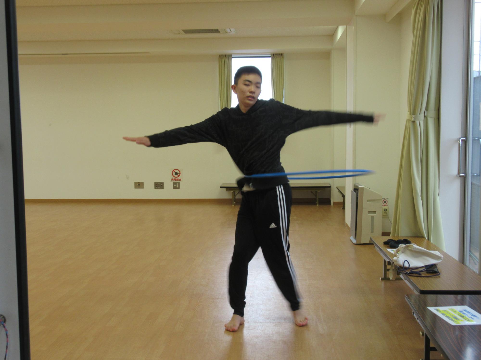 両手を広げ、フラフープを披露している中学生の写真
