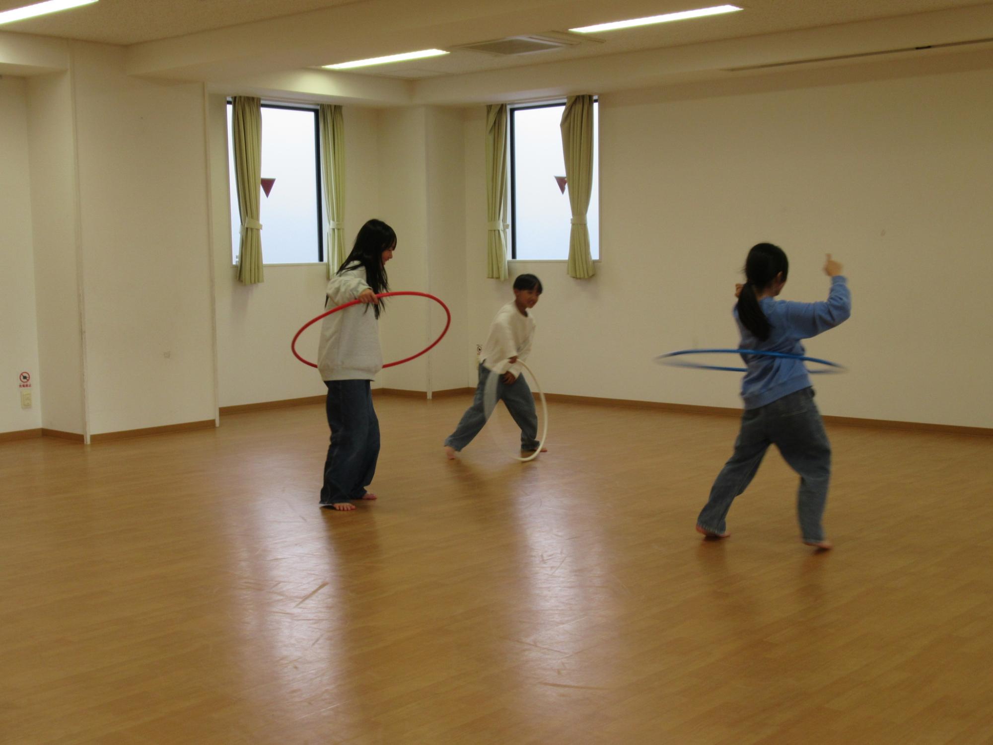 フラフープを楽しんでいる小学生3人組の写真