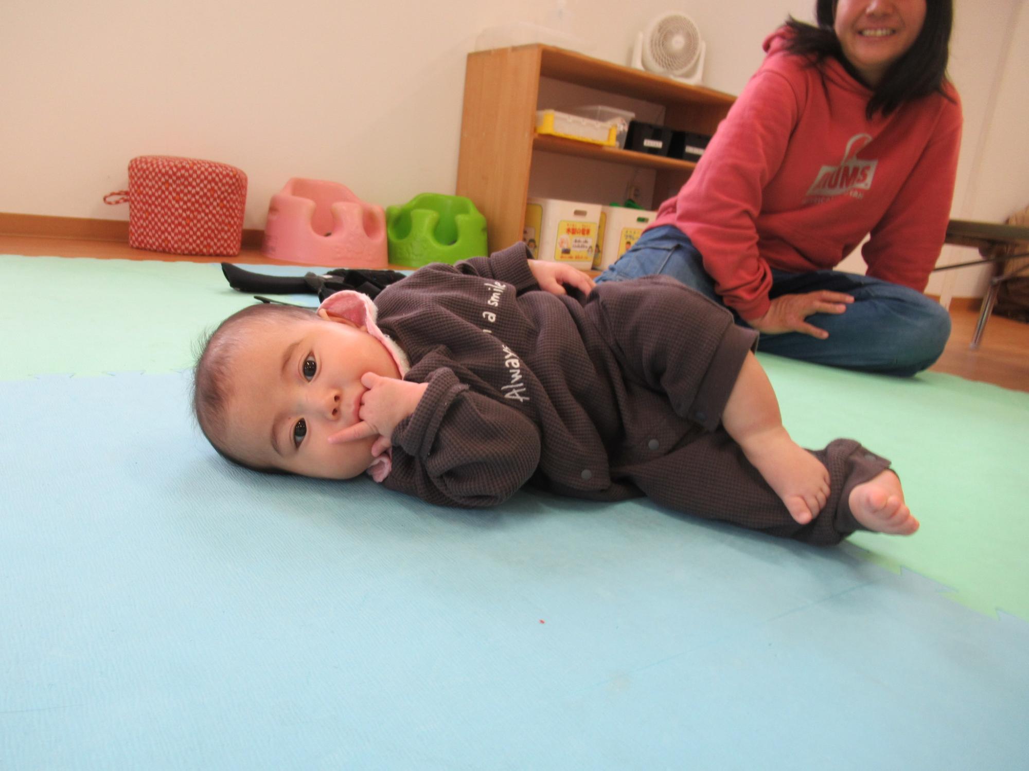 寝返りの練習をしている0歳児の写真